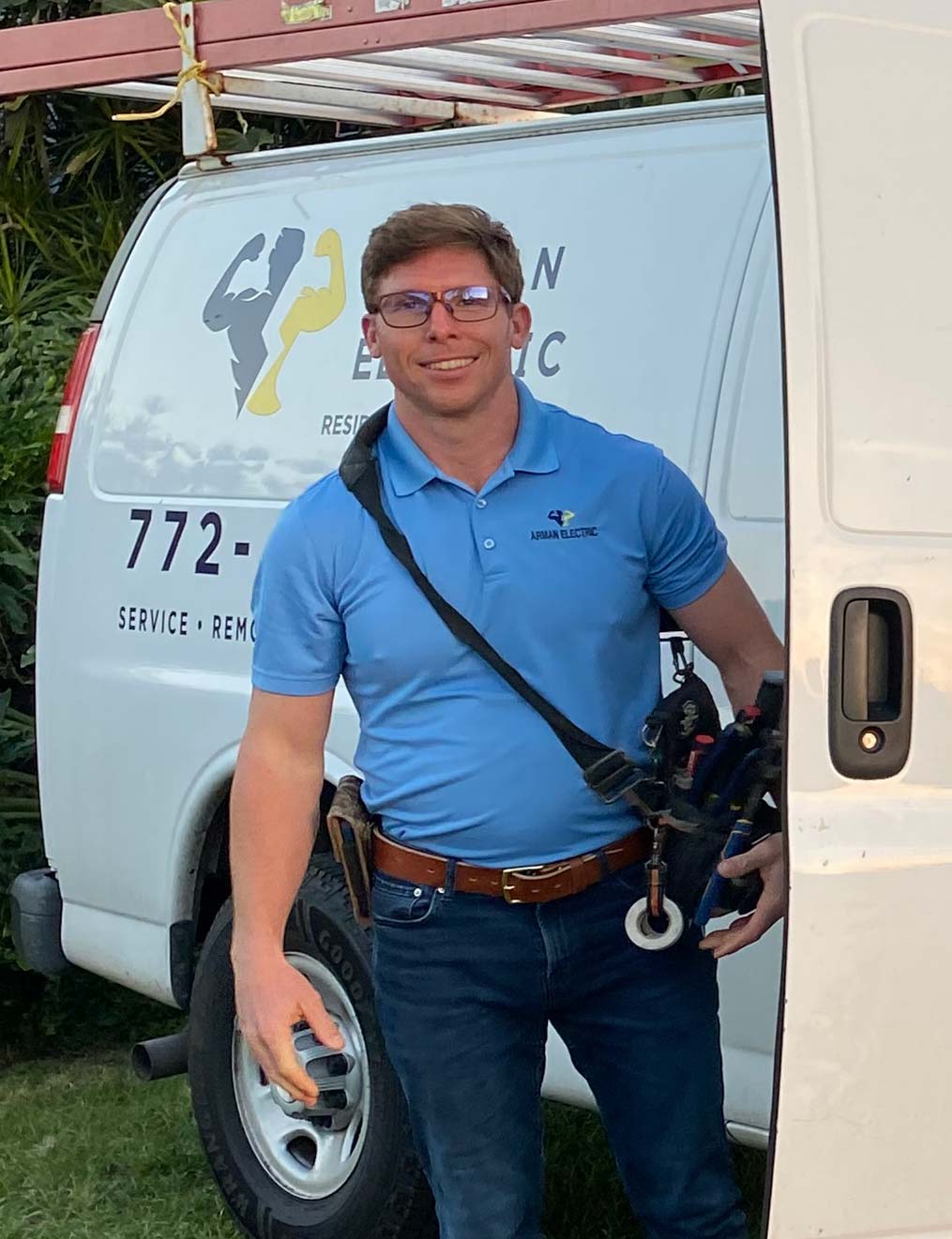 Sean VanArman, owner and founder of Arman Electric, standing beside the company van